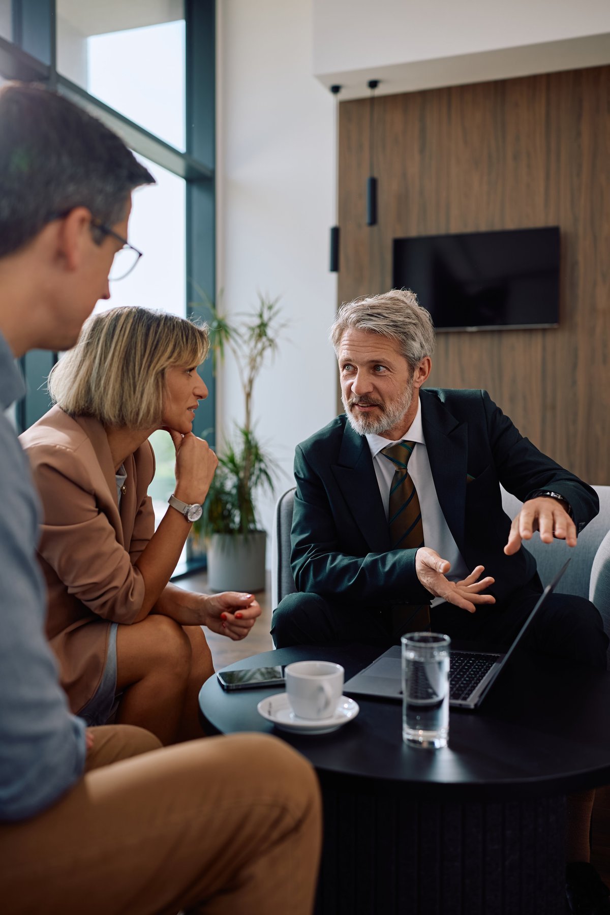 A mature financial advisor mentoring an investor couple during a consultation meeting